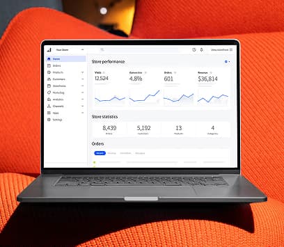 A laptop displaying an e-commerce store performance dashboard on an orange surface.